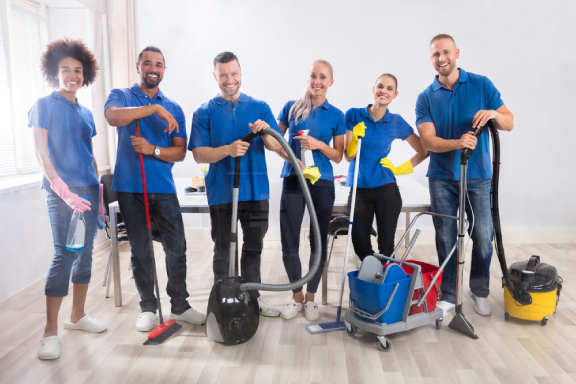 Office janitorial team cleaning desks and vacuuming floors in a modern workplace.