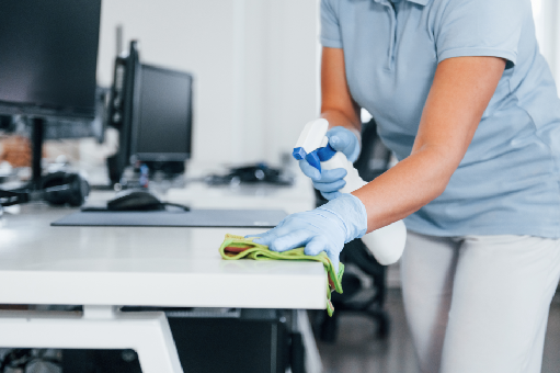 Office janitorial team cleaning desks and vacuuming floors in a modern workplace.