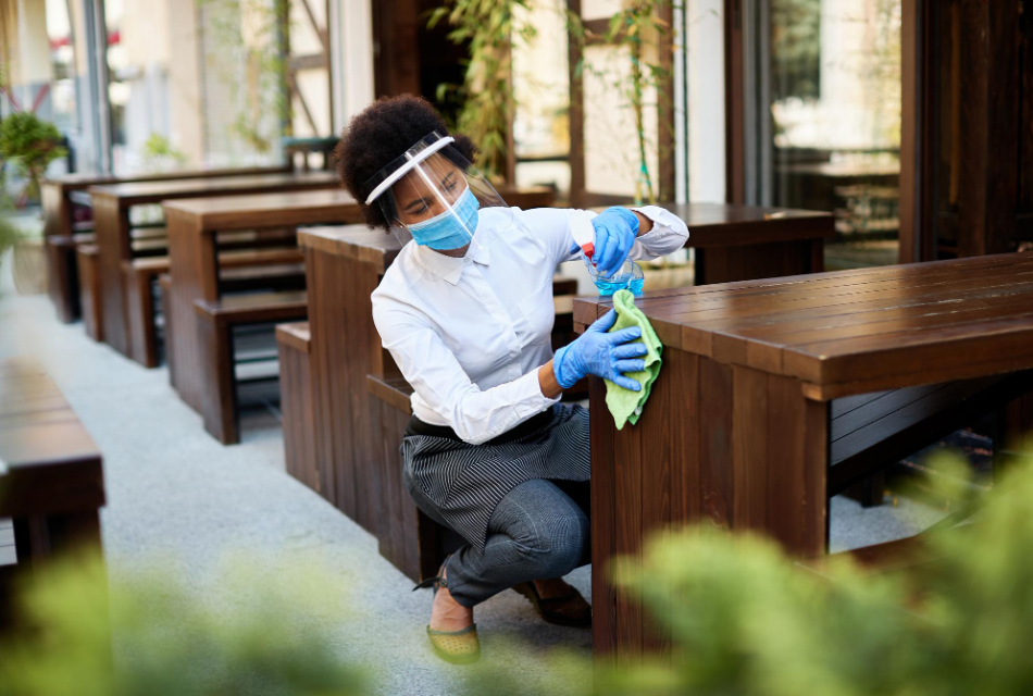 Janitorial professional disinfecting wooden pews inside a church sanctuary.